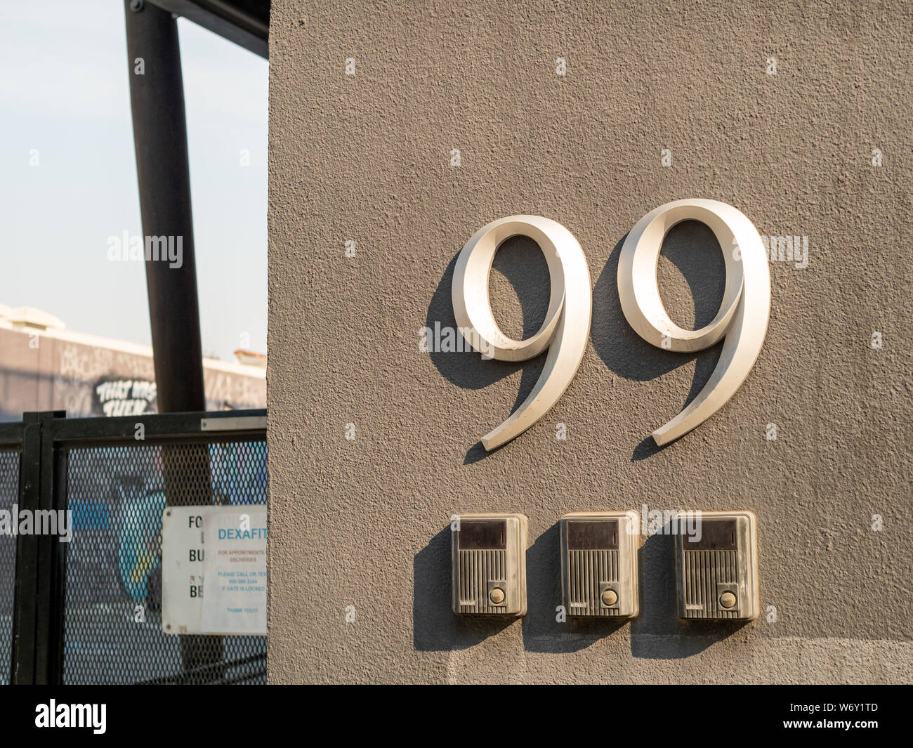 Numero 99 edificio segno appeso al di fuori dei cancelli di entrata Foto Stock