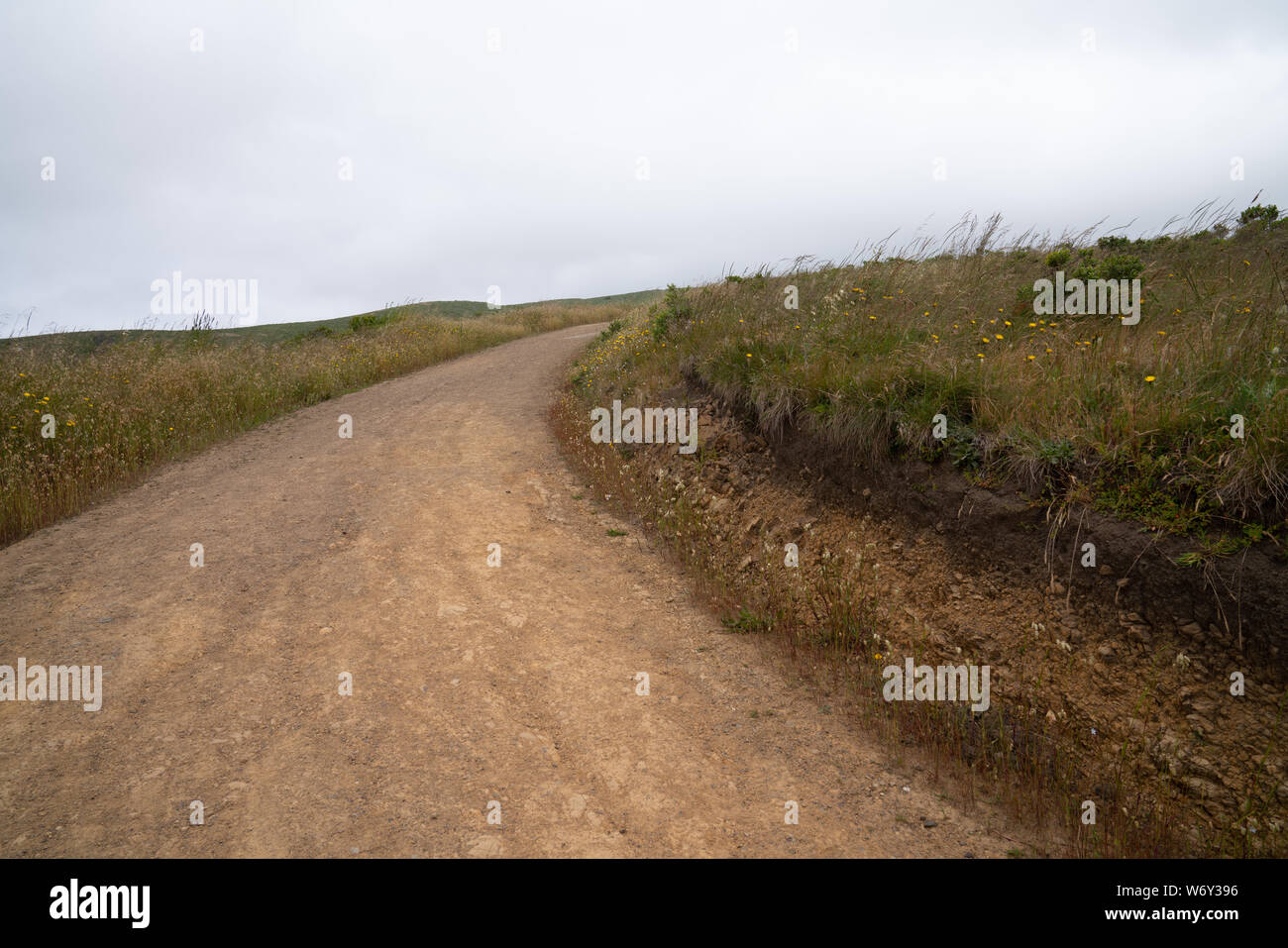 La sporcizia di avvolgimento sentiero escursionistico curvando a destra, senso di direzione sconosciuta nell orizzonte Foto Stock