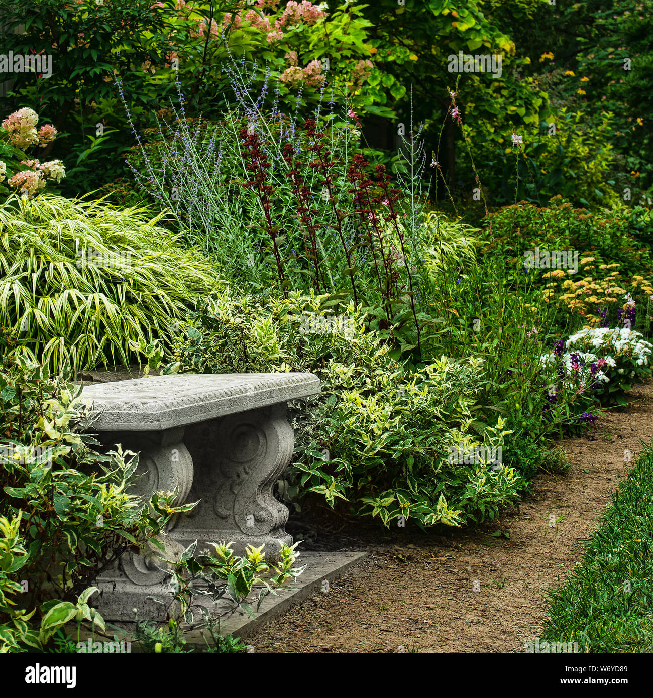 Vecchio banco in granito in un bellissimo giardino formale Foto Stock