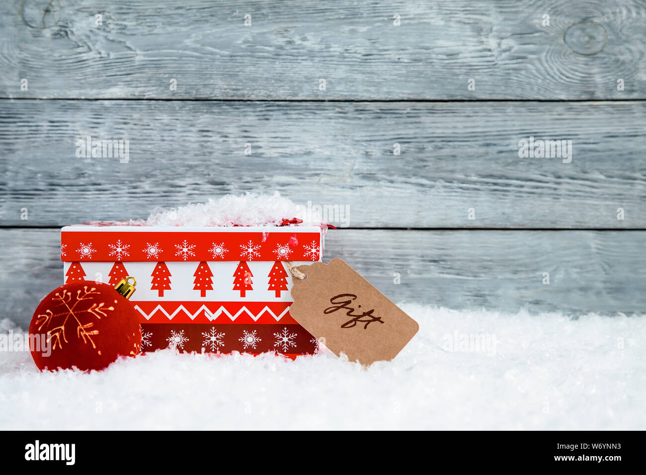 Rosso scatola di Natale sulla neve e lo sfondo di legno Foto Stock