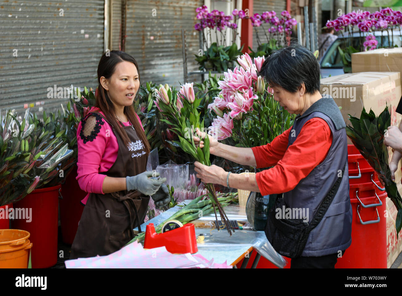 Il cliente valuta la qualità dei fiori recisi presso il Mercato dei Fiori di strada in Mong Kok, Hong Kong Foto Stock