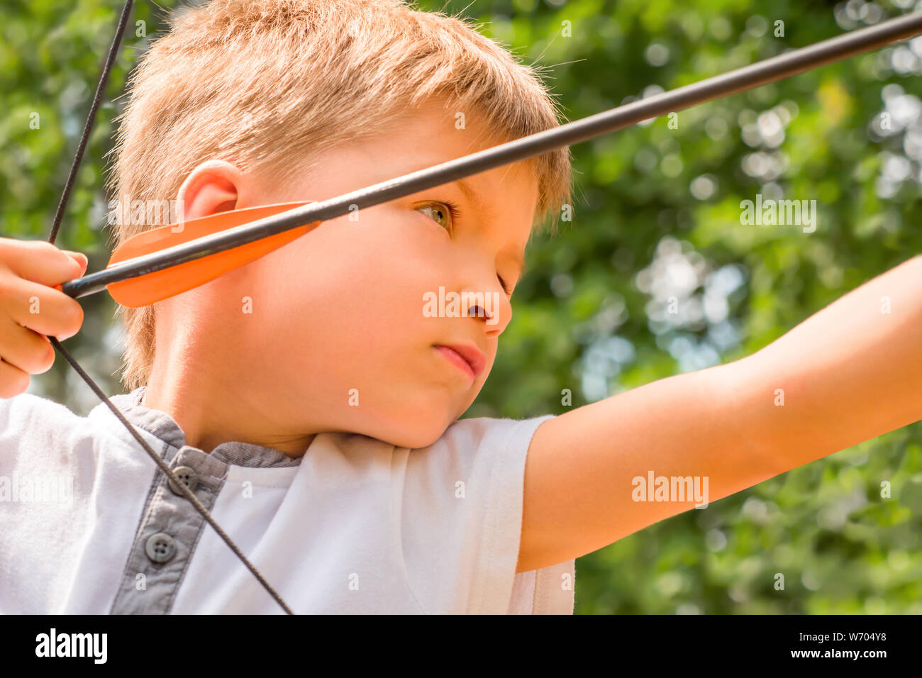 Scuola di tiro con l'arco. Ragazzo con un arco e frecce. Bambini e sport.  Sfondo