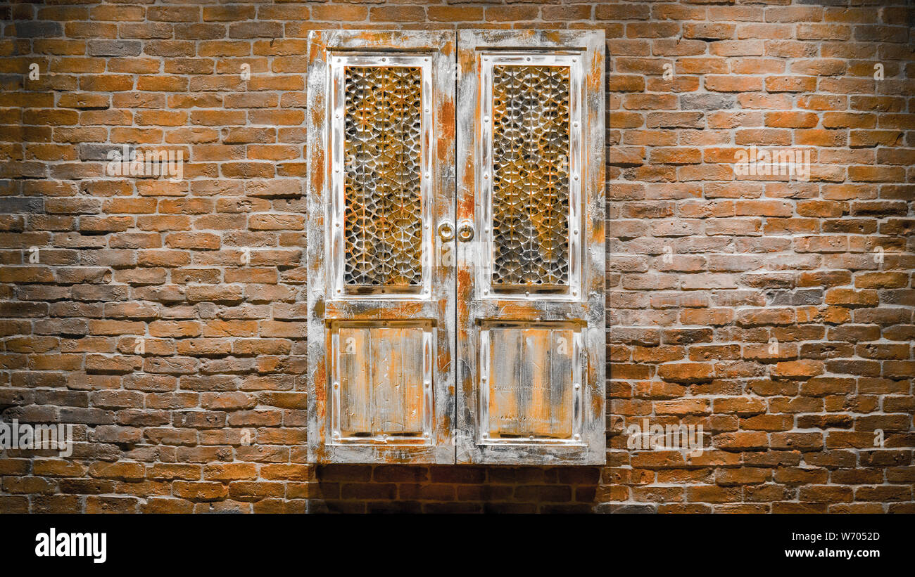 Decorativo porta appeso su un muro di mattoni. Finestra di legno su un muro di mattoni dello sfondo. Vintage vecchia porta di legno esterno. Vecchia porta di legno su un muro di mattoni. Sfondo vintage. Vecchio interno stile esterno Foto Stock