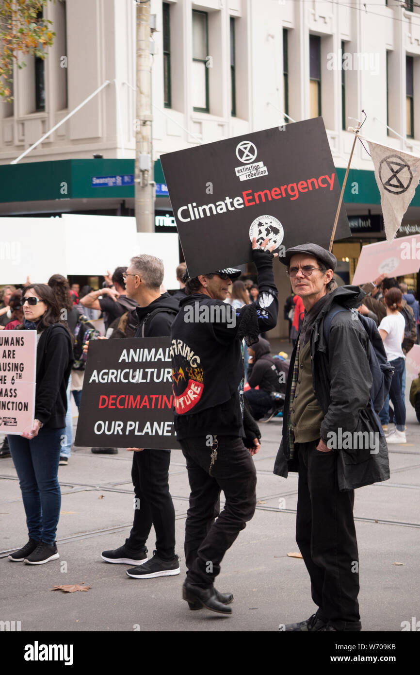 Medio di età compresa tra i manifestanti holding nero 'agricoltura animale sta decimando il nostro pianeta' segno di Melbourne, Australia clima marcia di protesta. Foto Stock