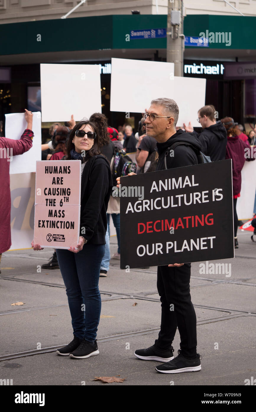 Medio di età compresa tra i manifestanti holding nero 'agricoltura animale sta decimando il nostro pianeta' segno di Melbourne, Australia clima marcia di protesta. Foto Stock