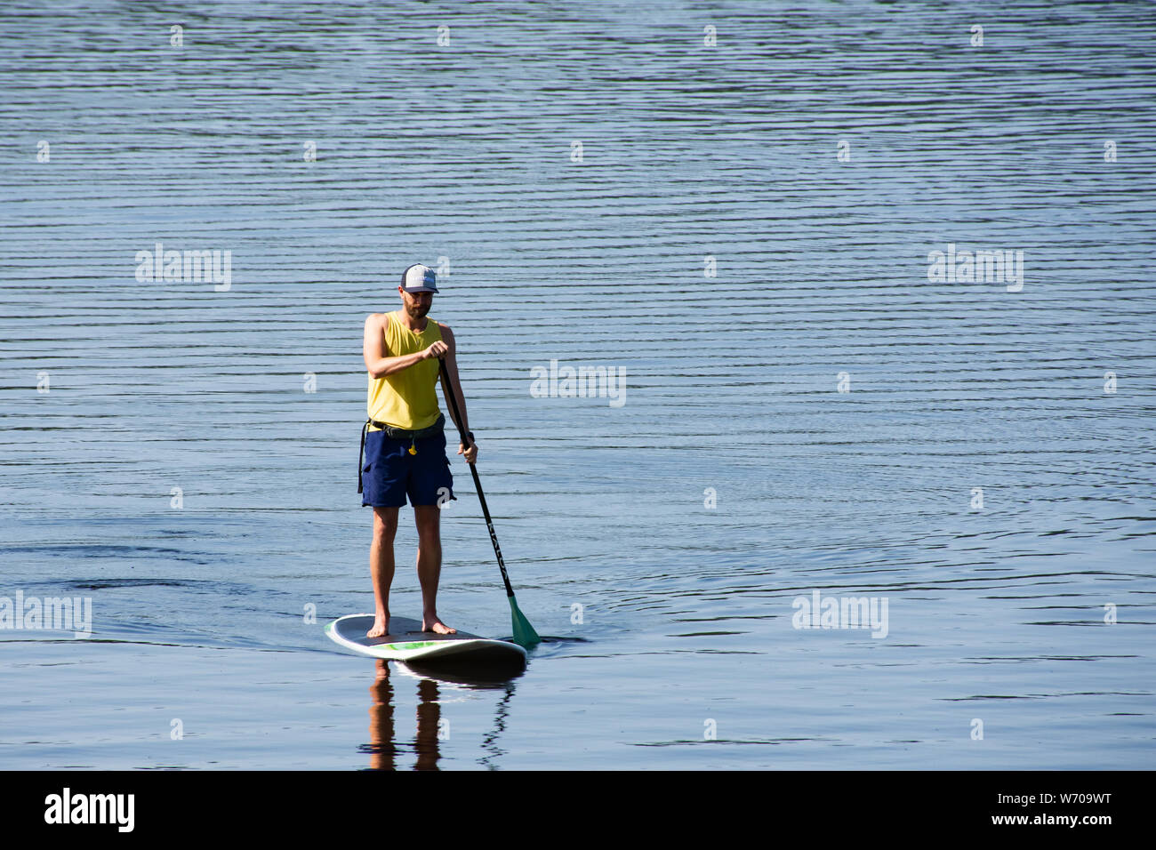 Un uomo paddling una racchetta board sul Lago Pleasant nelle Montagne Adirondack, NY USA Foto Stock
