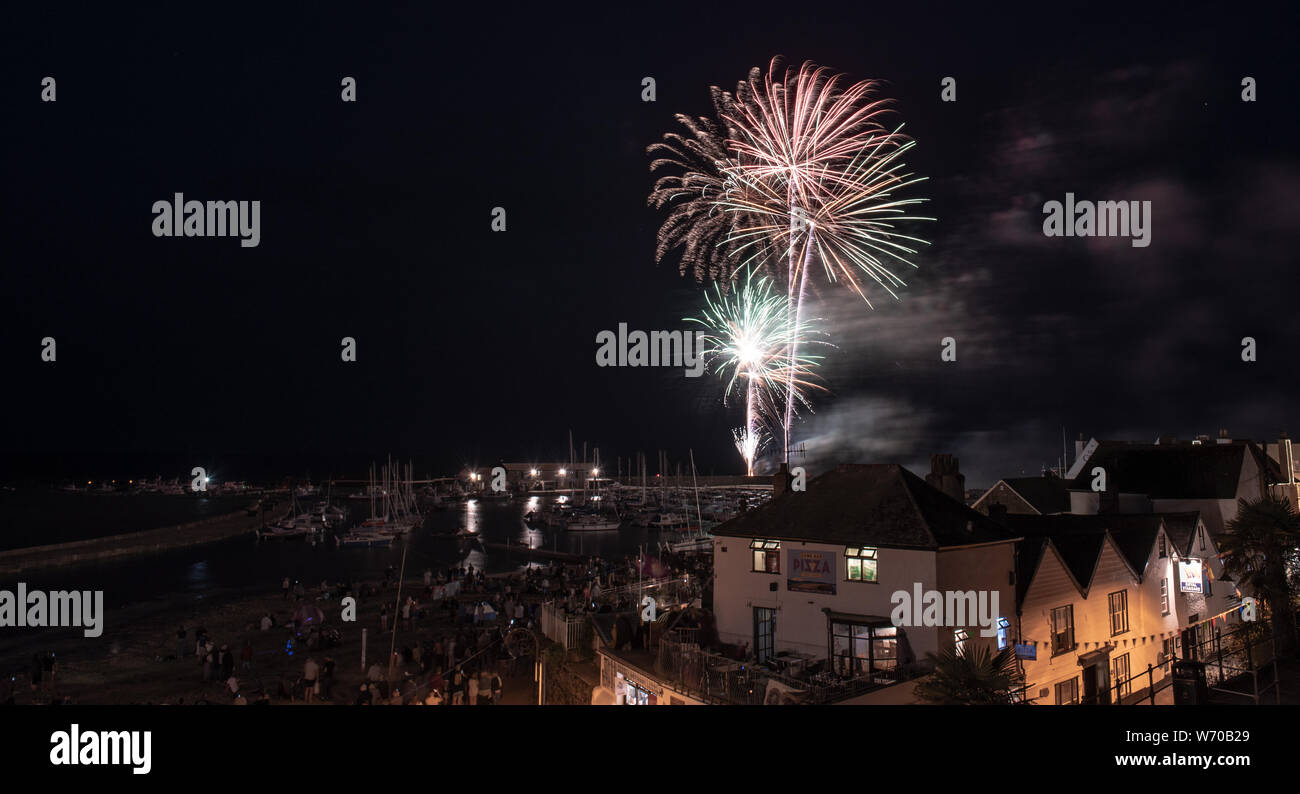 Lyme Regis, Dorset, Regno Unito. Il 3 agosto 2019. Meteo REGNO UNITO: folle raccogliere su un estati calde la sera per guardare il agosto annuale di fuochi d'artificio presso il porto di Cobb Lyme Regis. La Carità evento avviene ogni anno come parte della regata, il Carnevale e la scialuppa di salvataggio settimana ed è frequentato da gente del posto e i visitatori della città con molti ritornando di anno in anno. Credito: Celia McMahon/Alamy Live News. Foto Stock