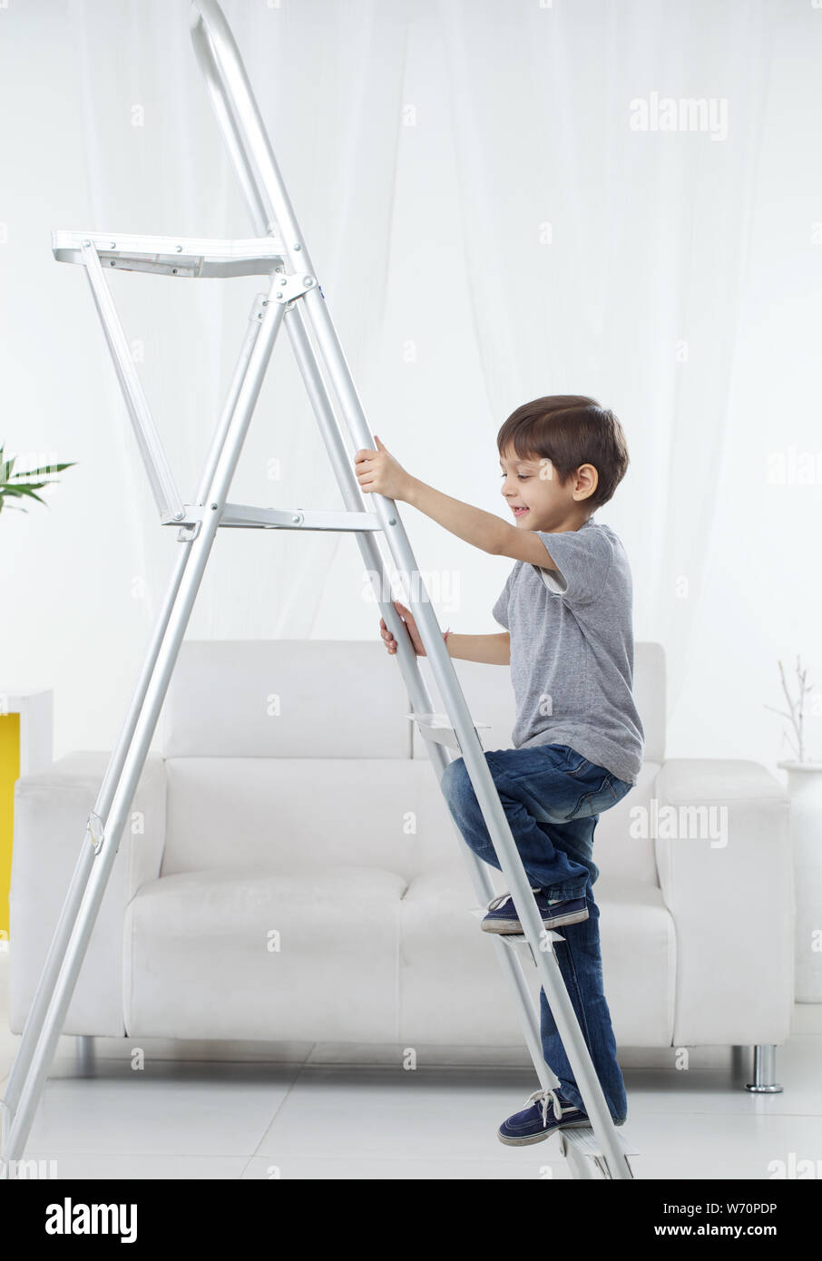 Ragazzo salendo una scala a pioli e sorridente Foto Stock