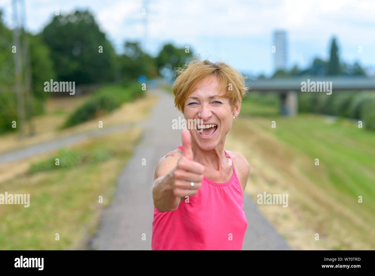 Donna entusiasta di dare un pollice in alto gesto con un raggiante gleeful smile come lei festeggia un successo personale o mostra il suo supporto e accordo Foto Stock