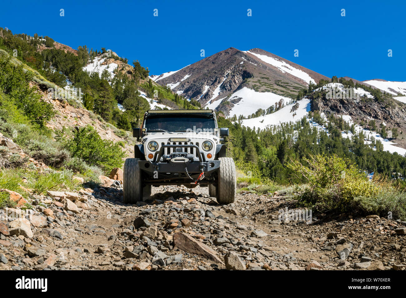 Jeep sulla strada sterrata in Sierras con picchi di montagna e valle verde Foto Stock