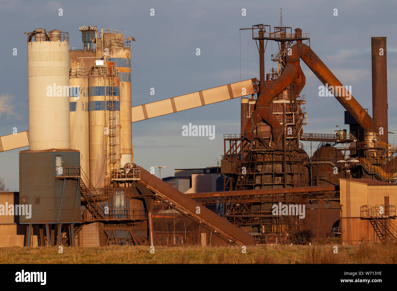 Foto di una sporca impianto siderurgico con fumnati ciminiere Foto Stock