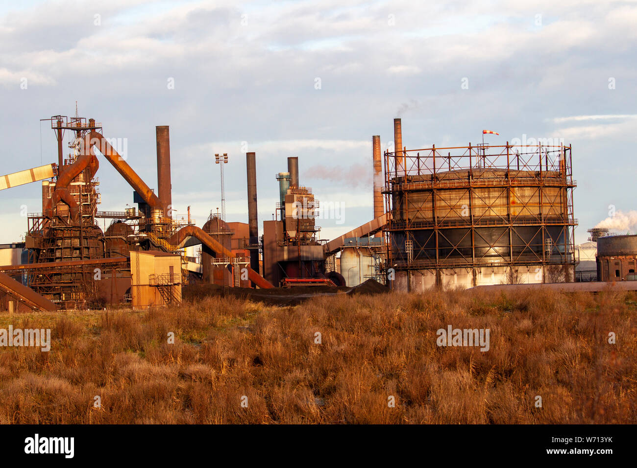 Foto di una sporca impianto siderurgico con fumnati ciminiere Foto Stock