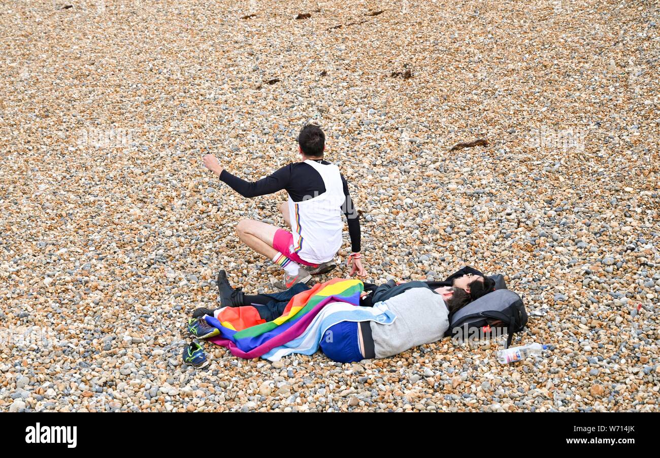 Brighton, Regno Unito. 4 agosto 2019. Brighton e Hove Pride festaioli prendere un inizio di mattina riposo in spiaggia il giorno dopo l'annuale Pride Parade attraverso la città . Migliaia di visitatori stanno frequentando il Brighton e Hove Pride eventi nel corso di questo fine settimana . Credito: Simon Dack/Alamy Live News Foto Stock