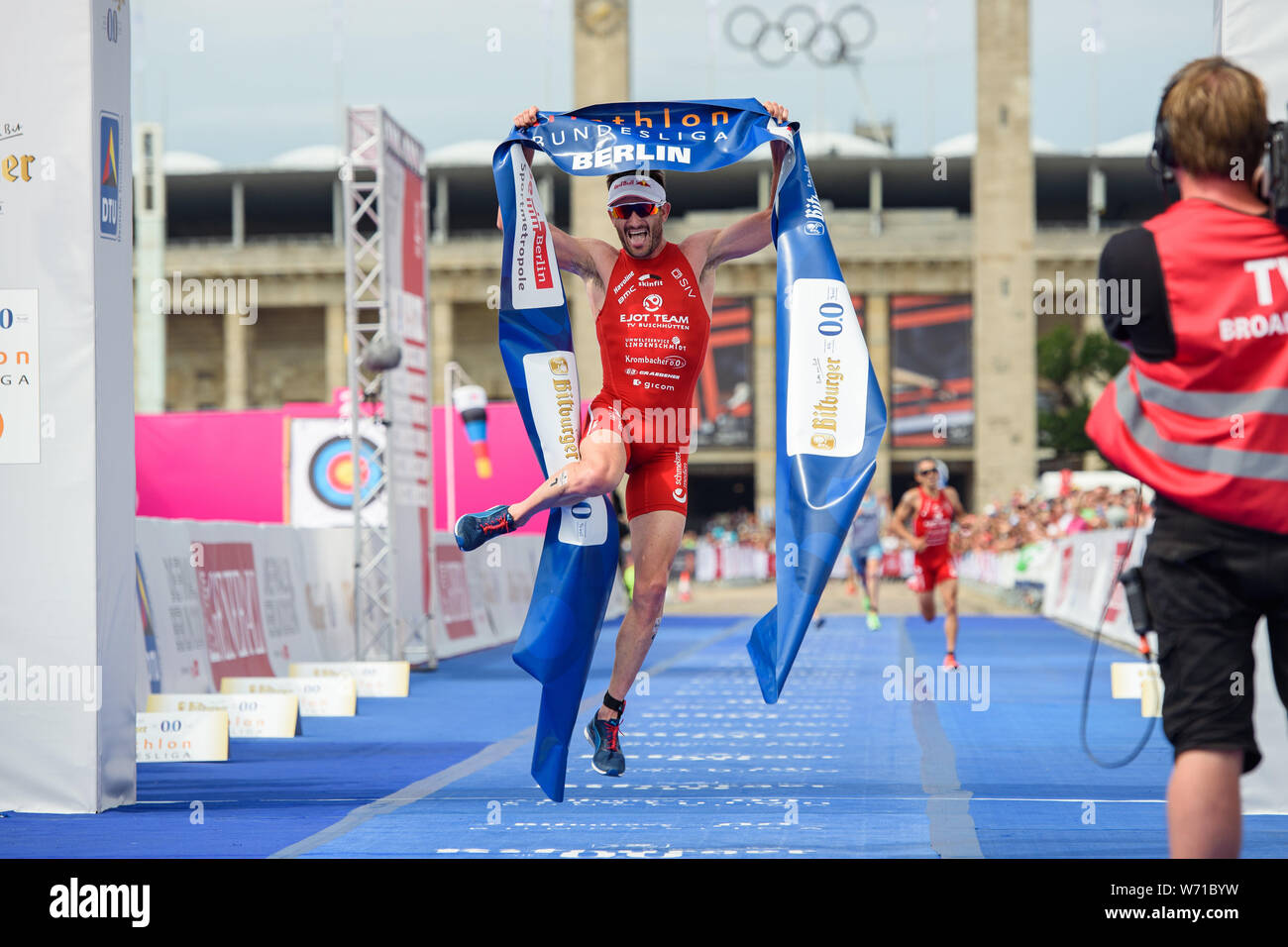 Berlino, Germania. 04 Ago, 2019. Triathlon: Campionato Tedesco, Olympic posto. Richard Murray è il primo a tagliare il traguardo sulla linea del traguardo di fronte allo Stadio Olimpico. Credito: Gregor Fischer/dpa/Alamy Live News Foto Stock