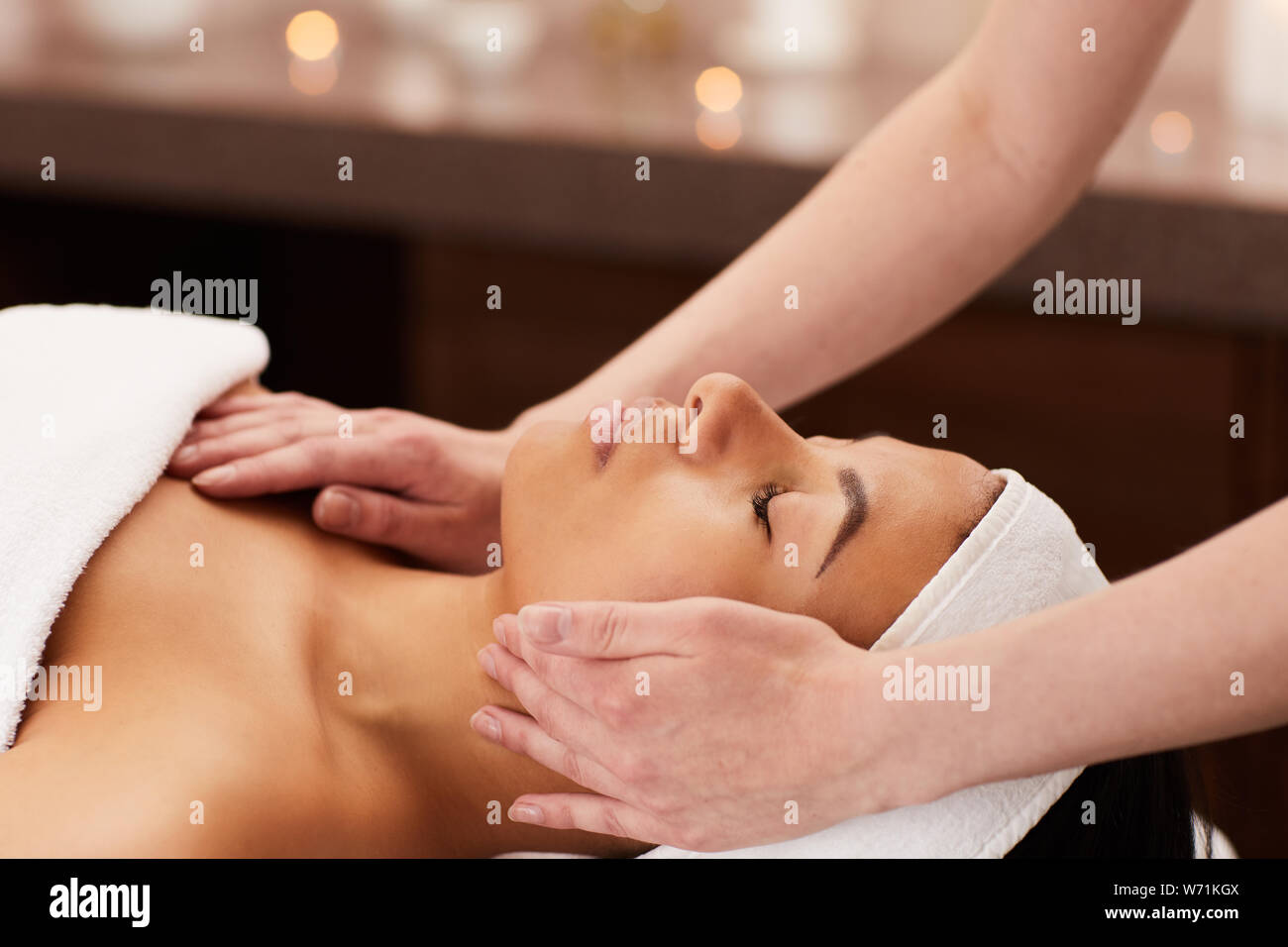 Vista laterale della bella mixed-gara donna godendo il massaggio del viso in una spa di lusso e spazio di copia Foto Stock