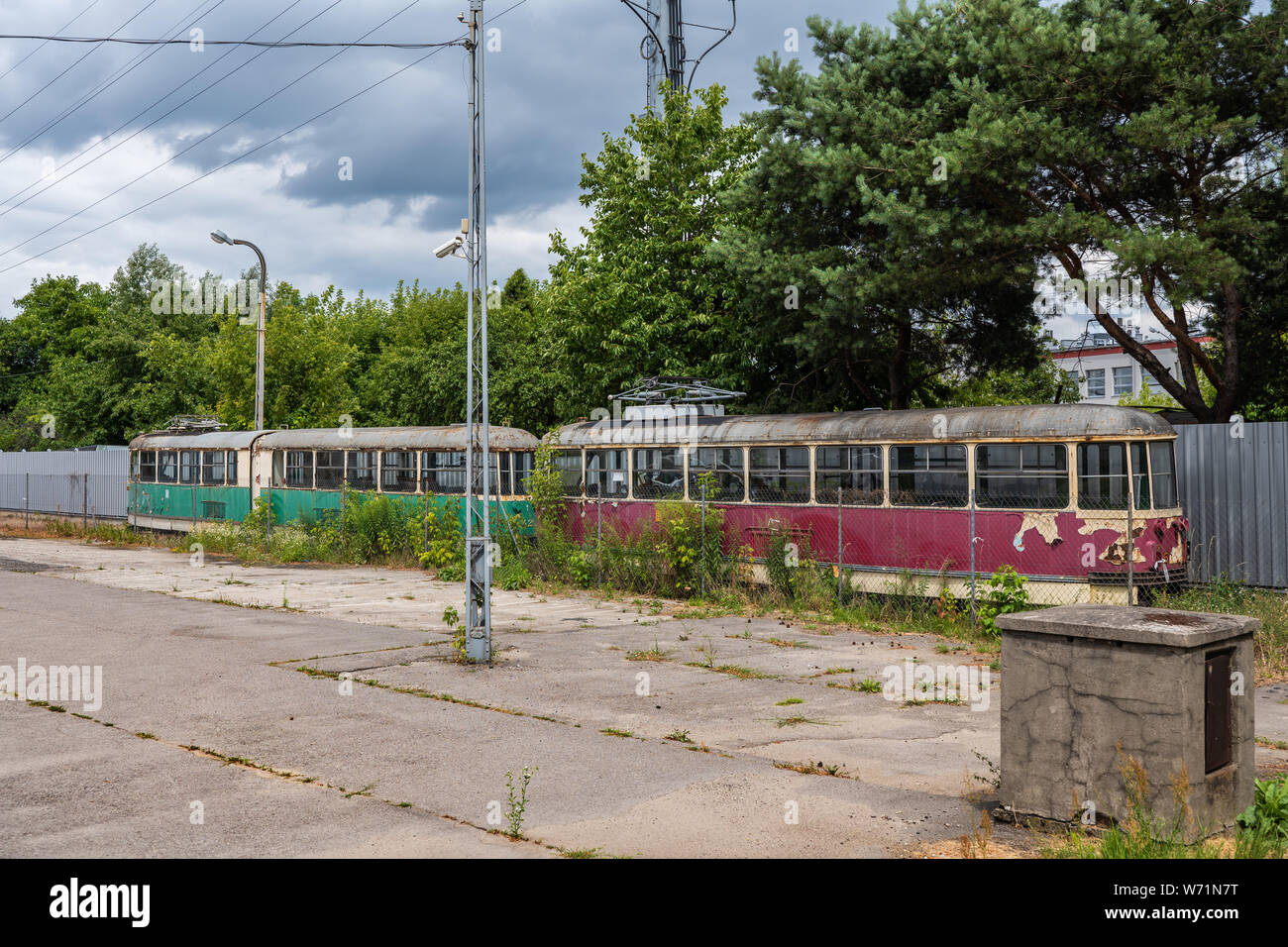 Abbandonato il tram d'epoca sul lato di un vecchio deposito, verde e rosso e veicoli su rotaia, obsoleto il trasporto pubblico a Varsavia, Polonia Foto Stock