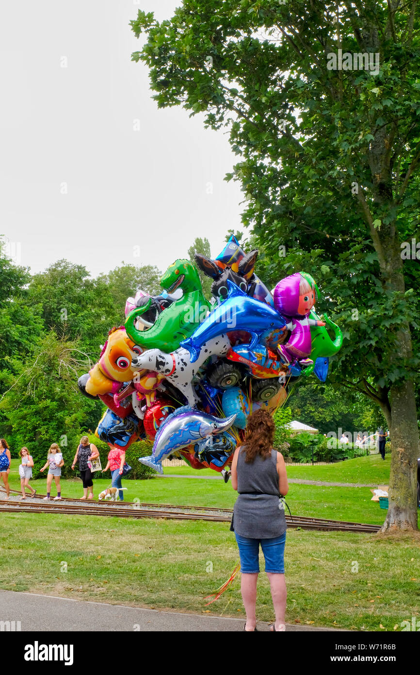Elio animale palloncini sagomati essendo tenuto da un palloncino venditore nel parco in estate a Bognor Regis, West Sussex, Regno Unito. Foto Stock