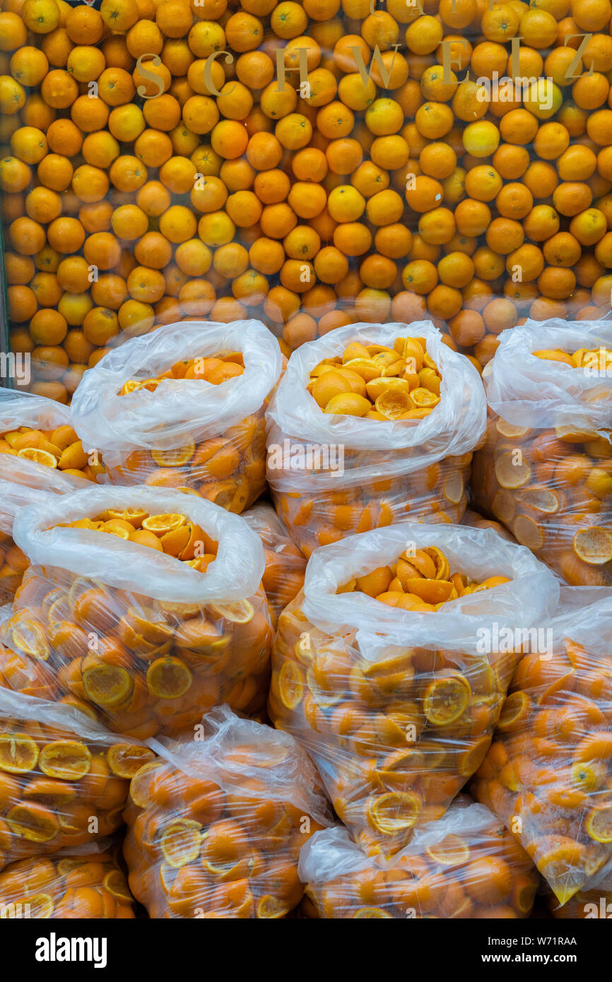 Arance accatastate in una finestra della barra di succo con sacchetti di bucce d'arancia schiacciate all'esterno Foto Stock