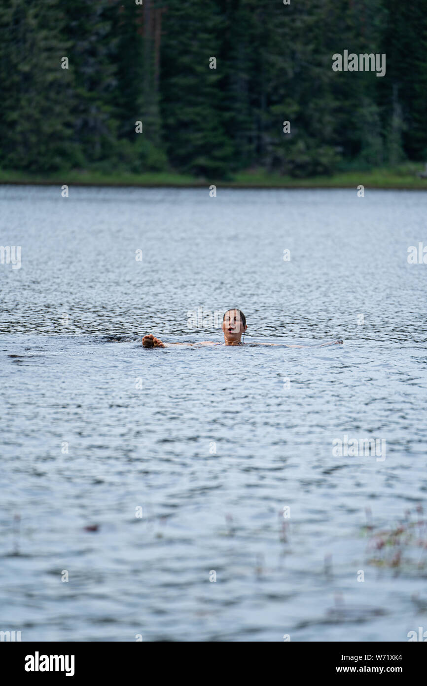 La donna selvatica nuotare nel fiume nero (Svartälven), Svezia. Galleggianti sulla sua schiena con i piedi e le dita dei piedi fuori dall'acqua Foto Stock