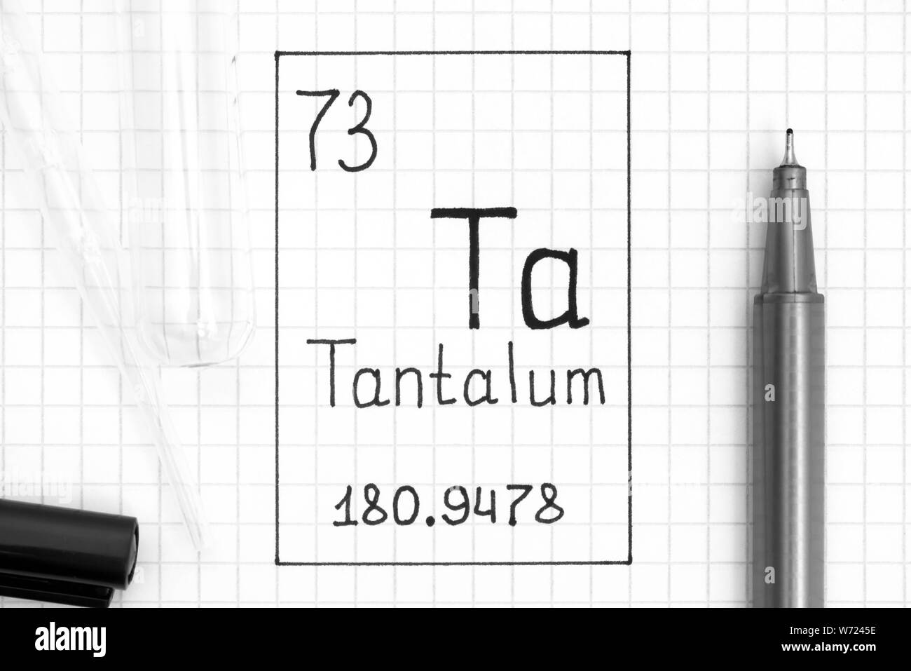 Tavola periodica degli elementi. La grafia elemento chimico tantalio Ta con la penna nera, tubo di prova e la pipetta. Close-up. Foto Stock