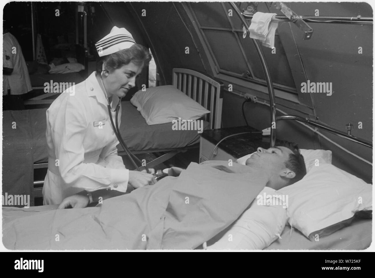 Da Nang, Vietnam del sud...Marina degli Stati Uniti infermiere tenente comandante Joan Brouilette controlla la condizione del PFC. Charles Smith come ella fa la sua quotidiana tornate il reparto cure intensive presso la Marina degli Stati Uniti Attività di supporto ospedale. Foto Stock