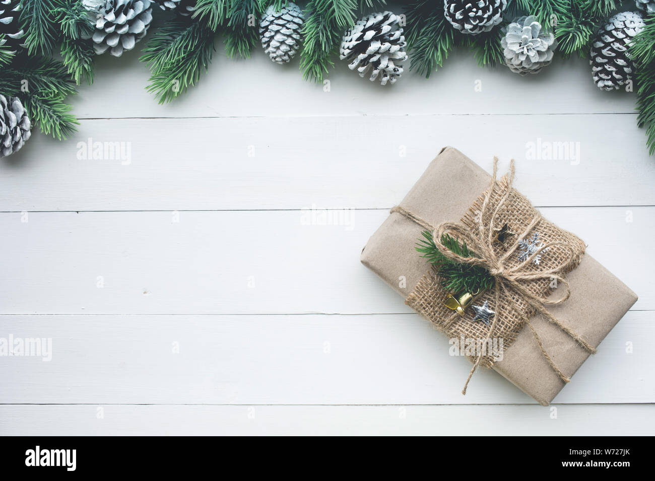 Confezione regalo avvolti in carta kraft con bordo di pino bianco su uno sfondo di legno.Per natale o nuovi concetti di yew idee.Lay piatto modello di progettazione Foto Stock