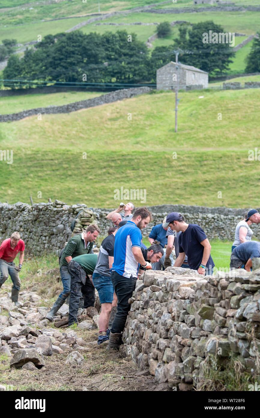 Yorkshire, Regno Unito. 04 Ago, 2019. Regno Unito - Meteo Reeth, North Yorkshire - 4 Agosto 2019 - il volontariato locale da giovani agricoltori club in North Yorkshire è sceso su di Reeth per ripristinare alcuni dei mitici stalattite mura distrutte da inondazioni martedì scorso. Credito: Wayne HUTCHINSON/Alamy Live News Foto Stock