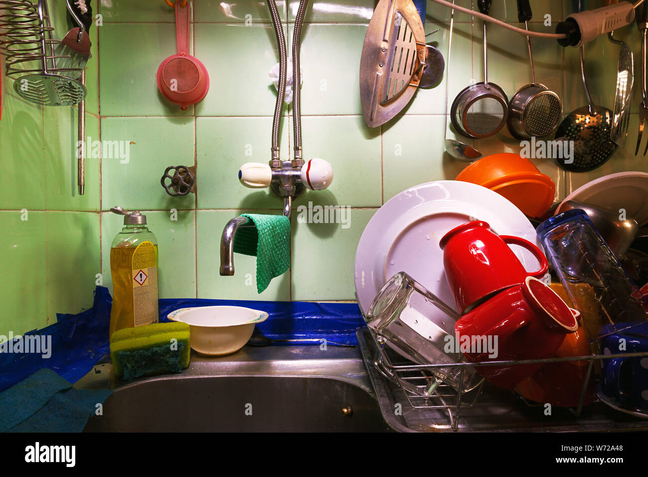 Vecchia cucina dettagli, lavato i piatti e posate e utensili antichi sulla parete piastrellata. Foto Stock