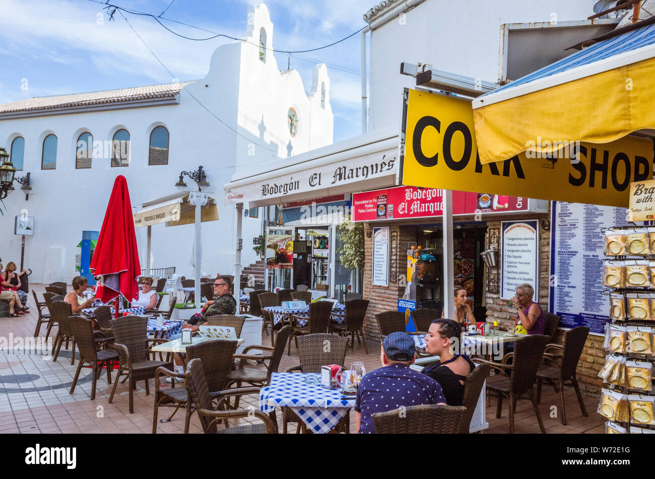 Torremolinos, provincia di Malaga, Andalusia, Spagna - Giugno 19th, 2019 : persone sedersi in un caffè all'aperto dalla chiesa di San Miguel al centro di Torrem Foto Stock
