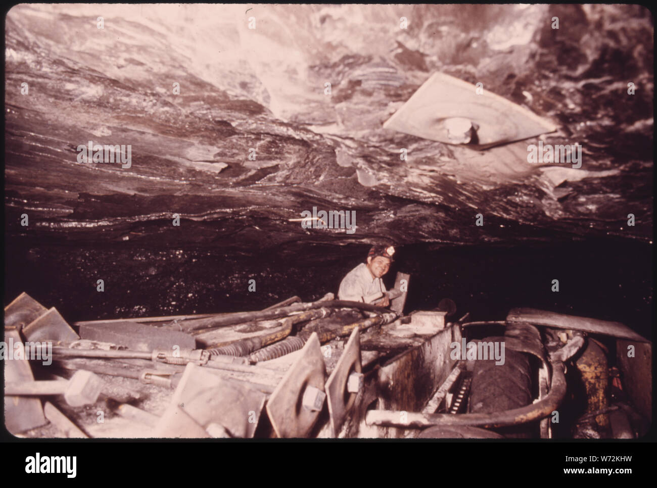 Il minatore LEE CALDWELL, su un mezzo semovente a tetto macchina bullonatura IN UNA MINIERA del Tennessee Consolidated Coal Company vicino a Jasper e CHATTANOOGA. La macchina ha un trapano che fori buchi nel soffitto dell'albero e viti automaticamente da quattro a cinque piedi di bulloni che agiscono come le bretelle per mantenere il tetto dalla caduta. IN PRIMO PIANO SUPERIORE è un bullone che è appena stato praticato in. Questo metodo riduce il numero di legno posti necessari come supporti antisismici. Questo è il più pericoloso il lavoro nelle miniere Foto Stock