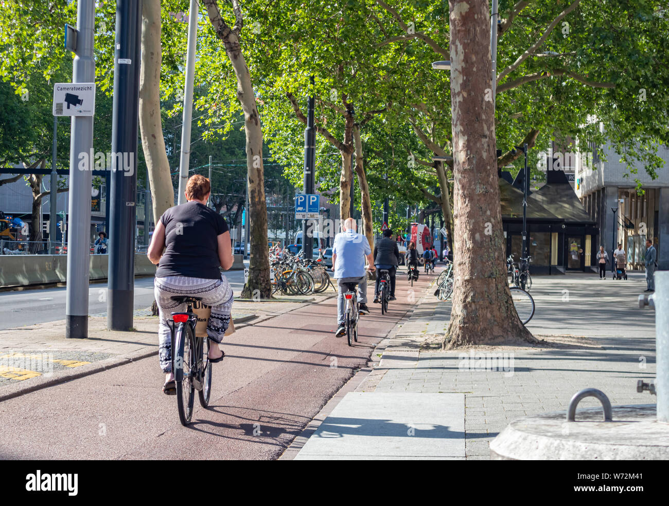Rotterdam, Paesi Bassi. Giugno 27, 2019. Vista posteriore di persone a cavallo di biciclette in centro città, molla giornata di sole Foto Stock