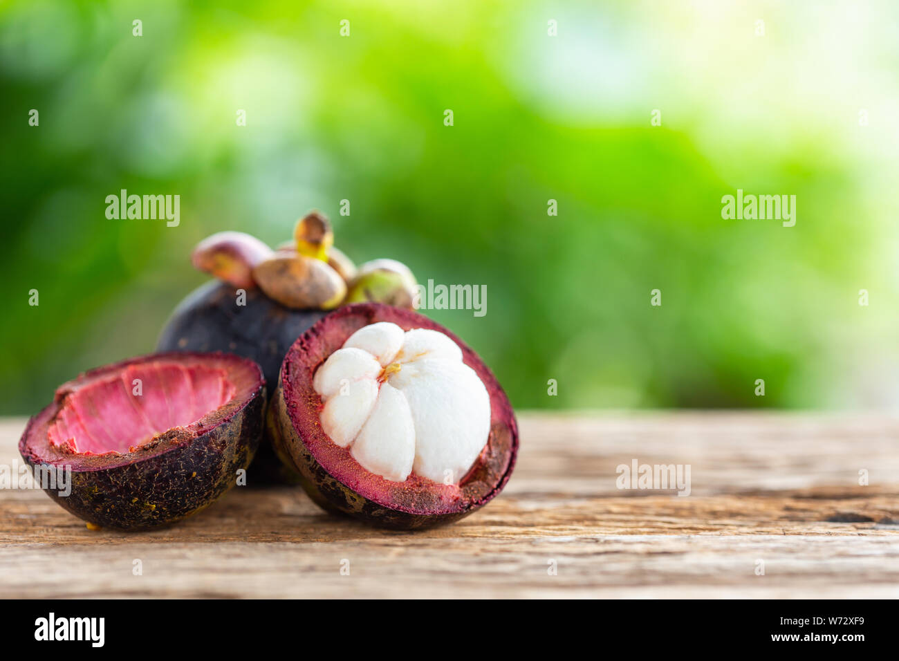 Mangosteen viola di frutta sul tavolo di legno con sfondo verde luce di sfocatura dello sfondo spazio per testo, disegno, fotografia montaggio o pubblicità Foto Stock