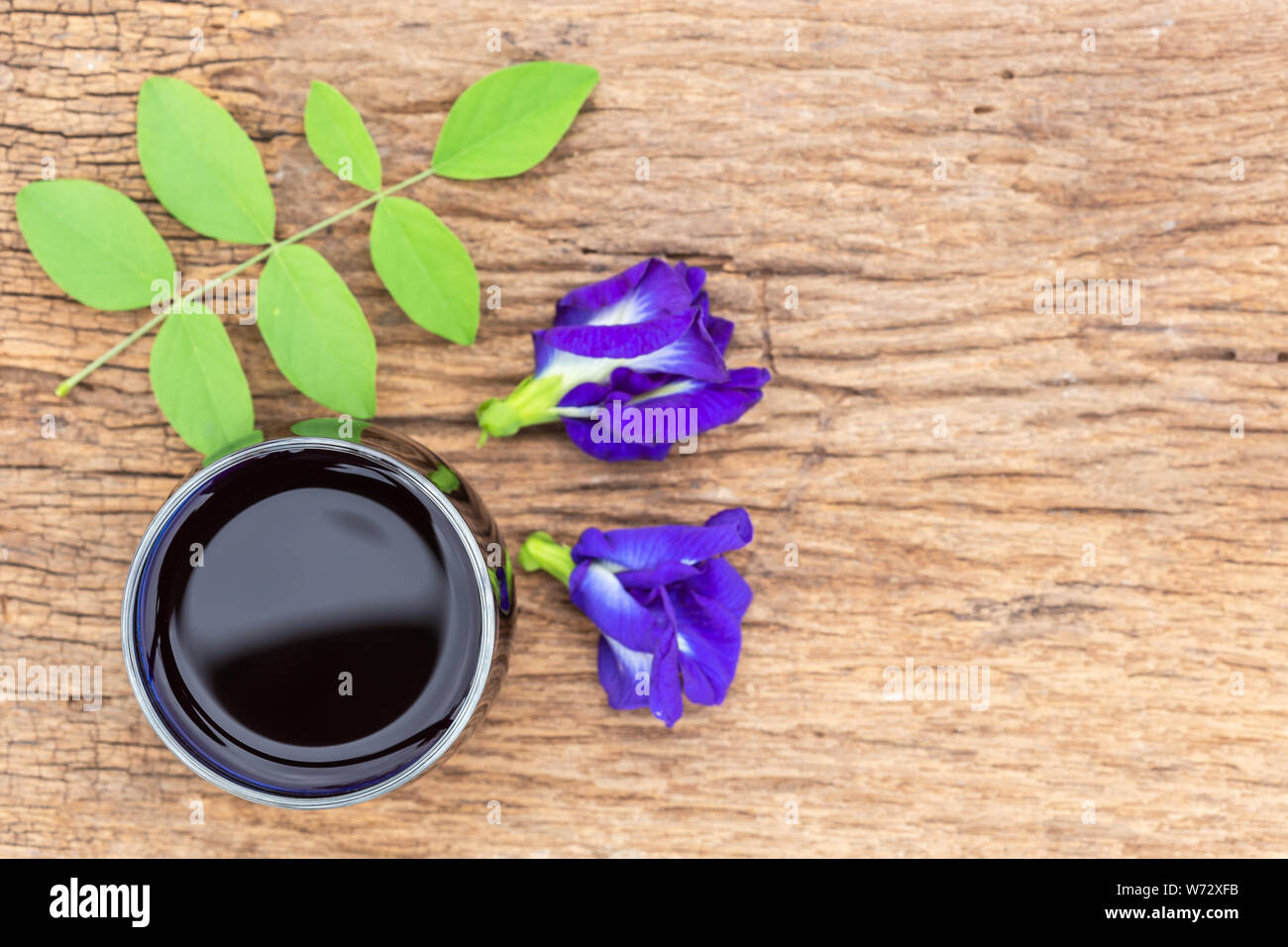 Vista dall'alto viola fresca Butterfly pea o blu fiore di pisello e succhi di frutta in vetro su un tavolo di legno sfondo Foto Stock