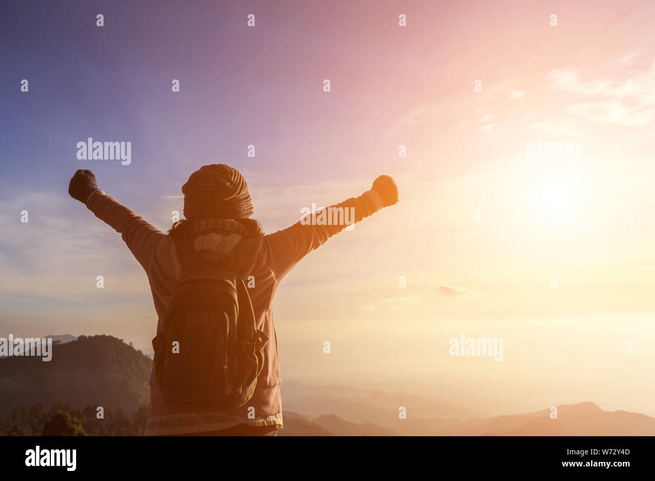 Donna con zaino in piedi sulla cima di una montagna con le mani alzate, sensazione di successo concept Foto Stock