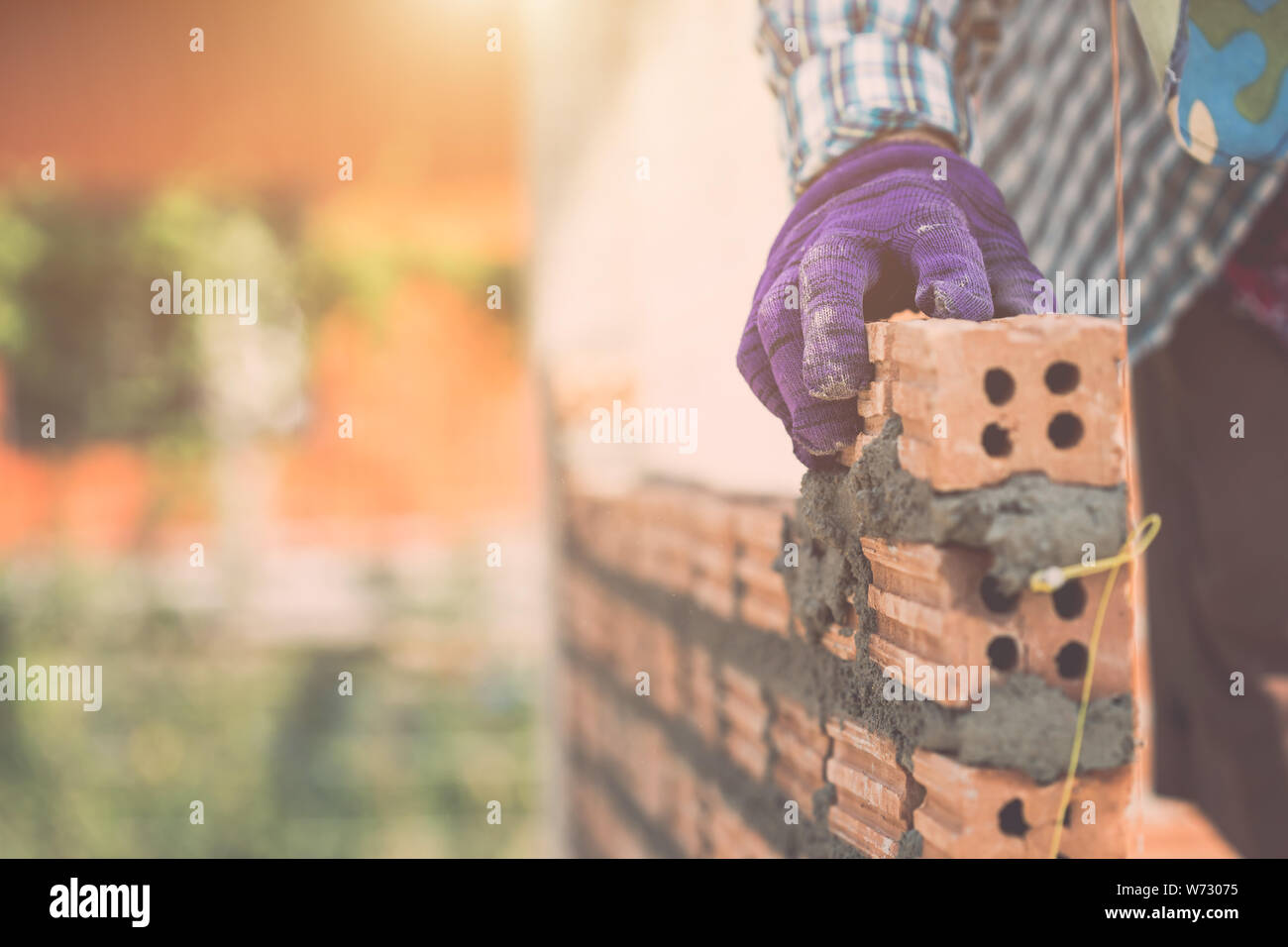 Operaio edile installazione di muro in mattoni nel processo di costruzione di casa Foto Stock