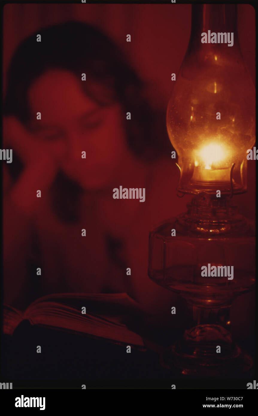 La lettura e lo studio da lampade a cherosene divennero più comuni come le persone hanno cercato di risparmiare elettricità. Questa persona è utilizzando una lampada Foto Stock