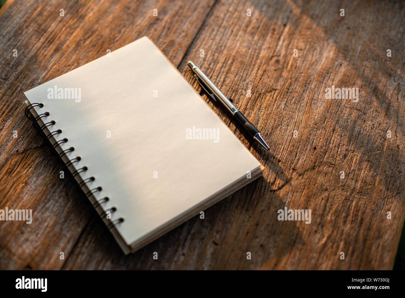 Vista superiore del libro bianco sul vecchio tavolato in legno con uno sfondo con natura di mattina la luce del sole Foto Stock