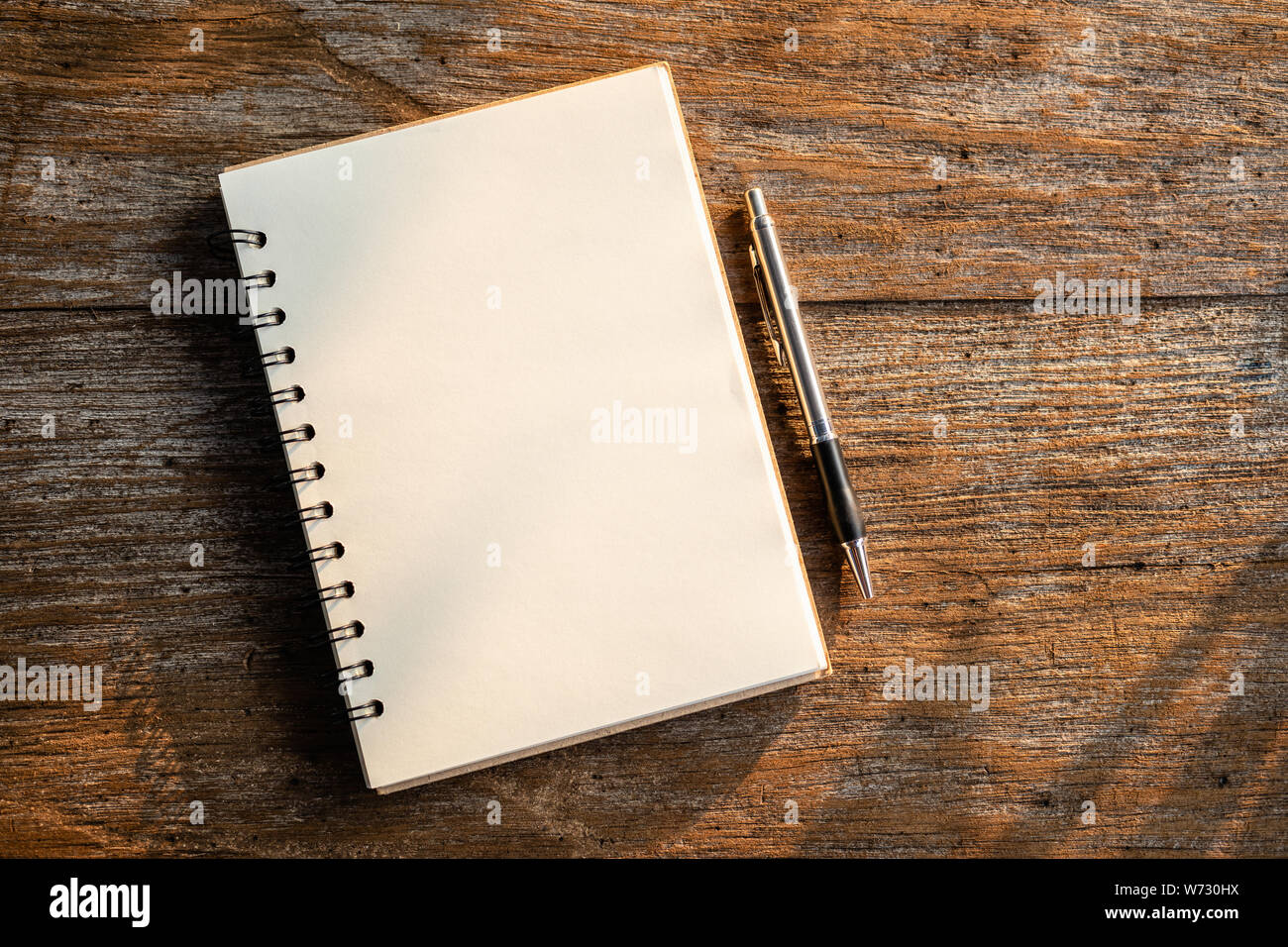 Vista superiore del libro bianco sul vecchio tavolato in legno con uno sfondo con natura di mattina la luce del sole Foto Stock