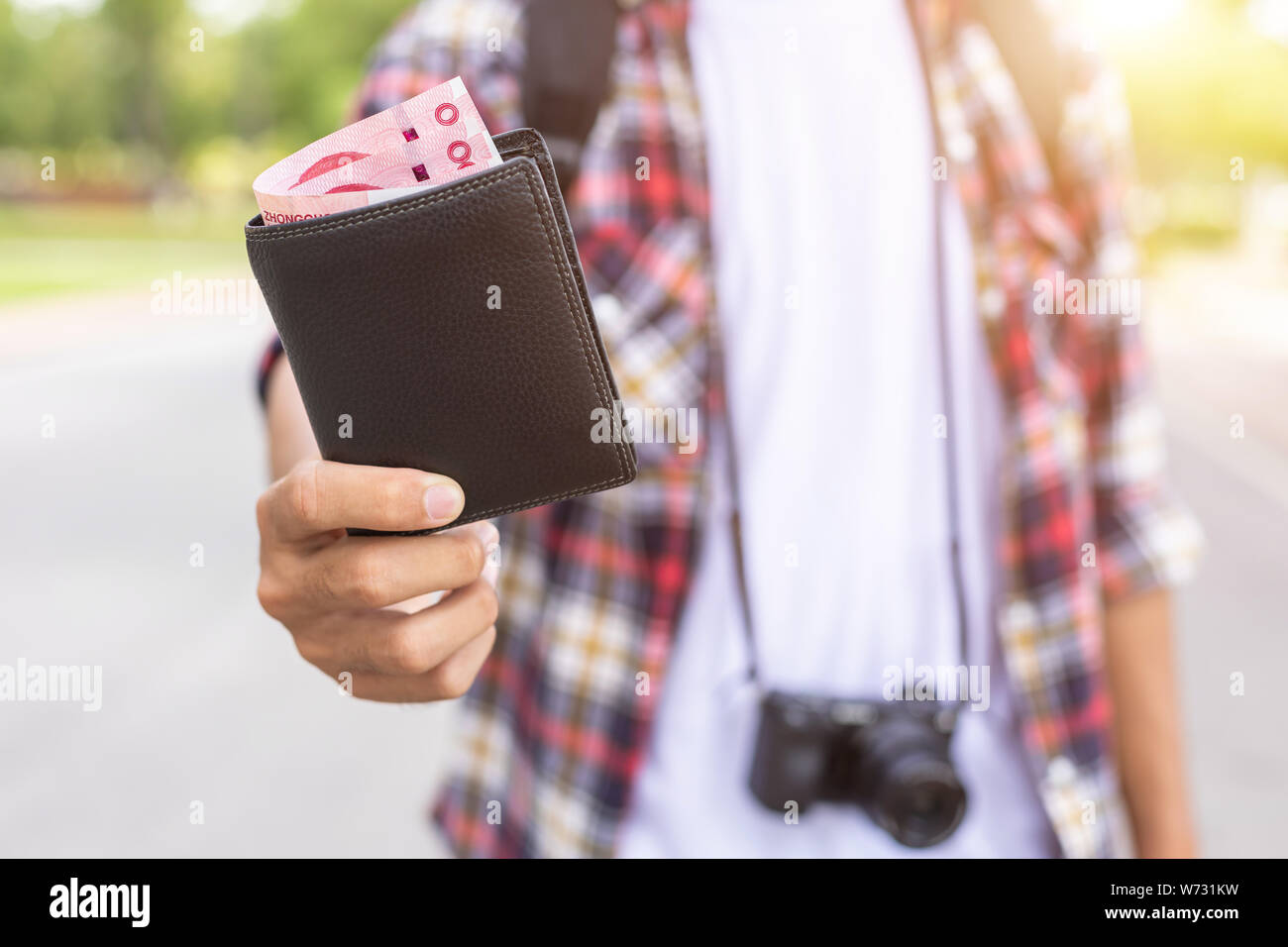 Mano di turisti asiatici dando la banconota e portafoglio nero che ha trovato in attrazione turistica. Perdere il concetto di portafoglio Foto Stock