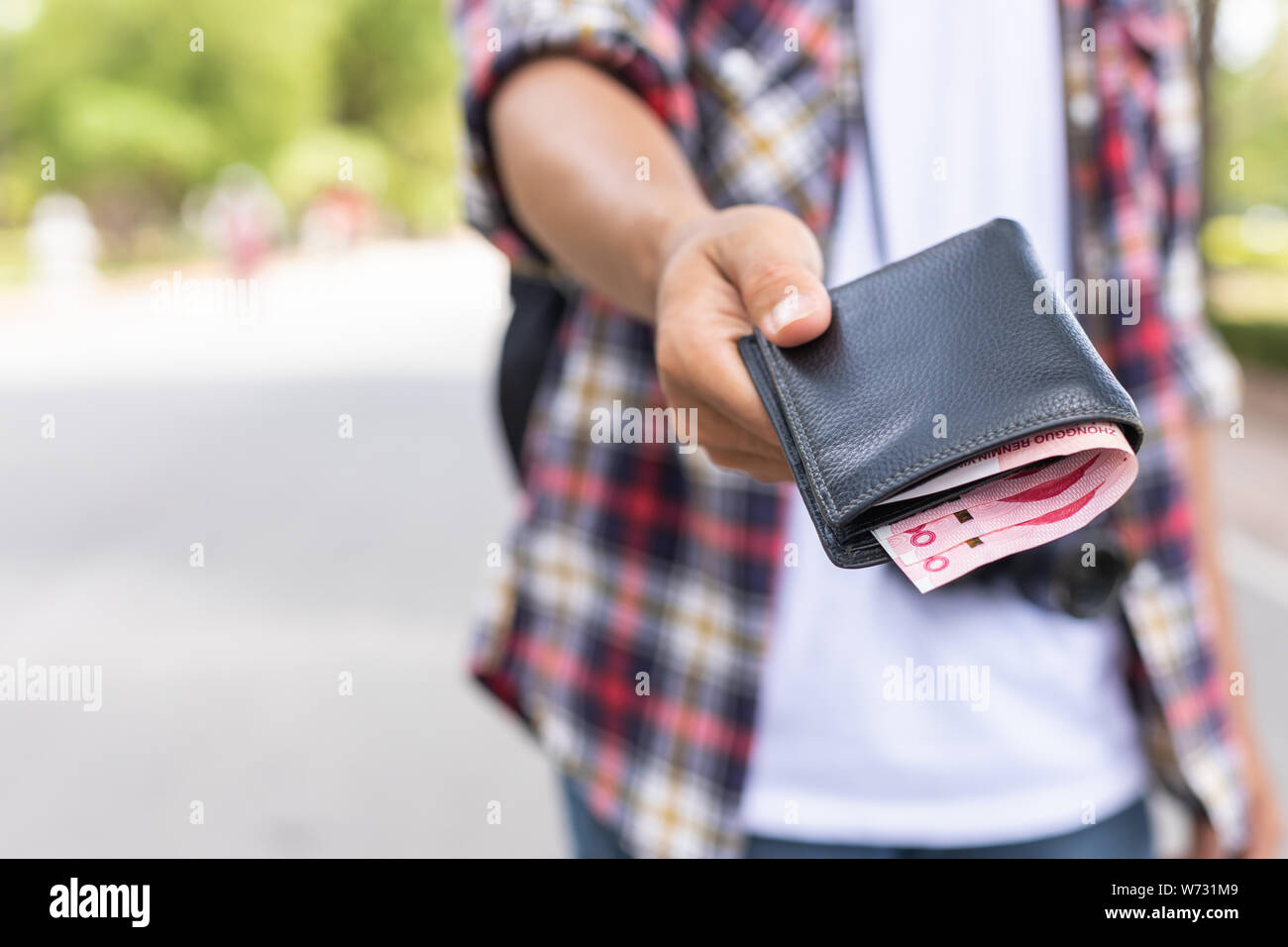 Mano di turisti asiatici dando la banconota e portafoglio nero che ha trovato in attrazione turistica. Perdere il concetto di portafoglio Foto Stock