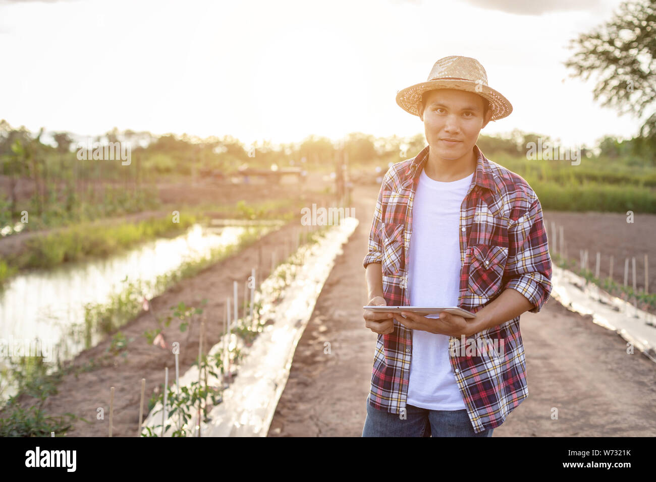 Ritratto di giovani asiatici agricoltore smart holding tablet nella sua azienda agricola biologica. Tecnologia e concetto di agricoltura Foto Stock