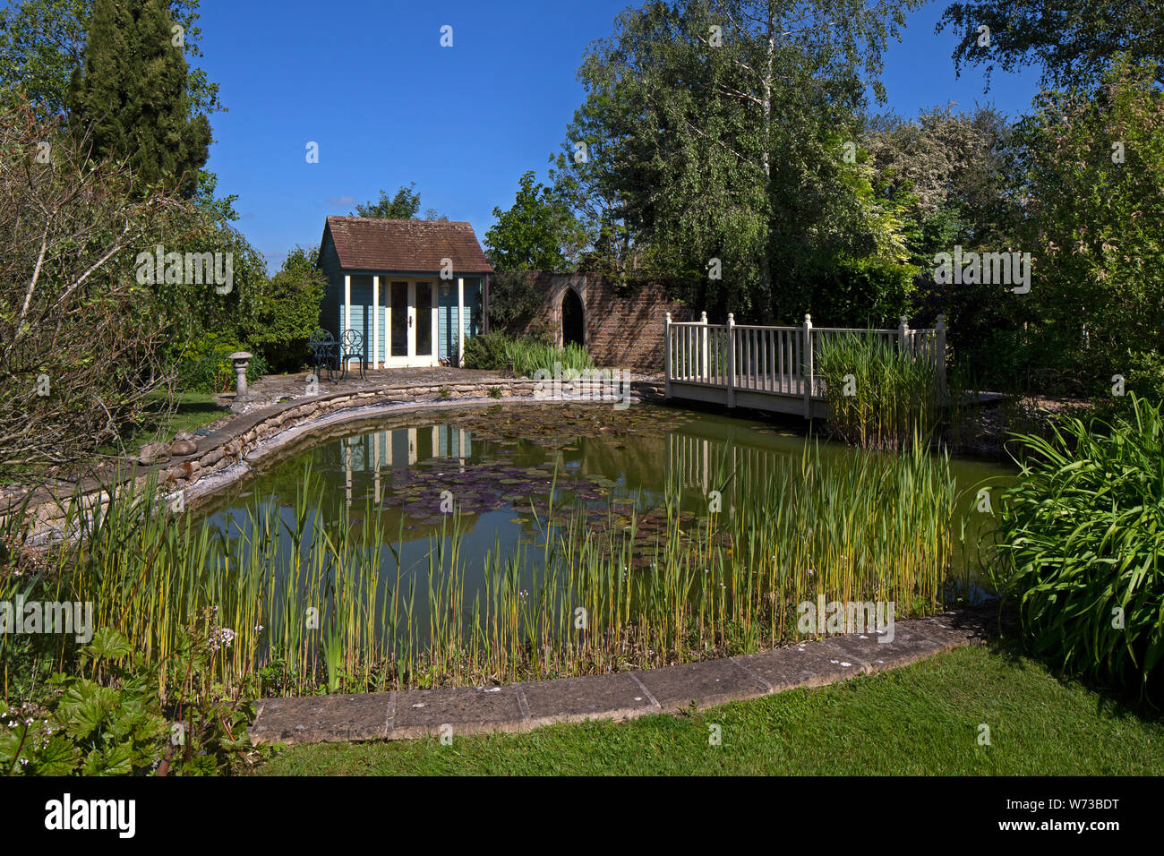 Summerhouse oltre alla ricerca di un laghetto in giardino inglese, Inghilterra Foto Stock
