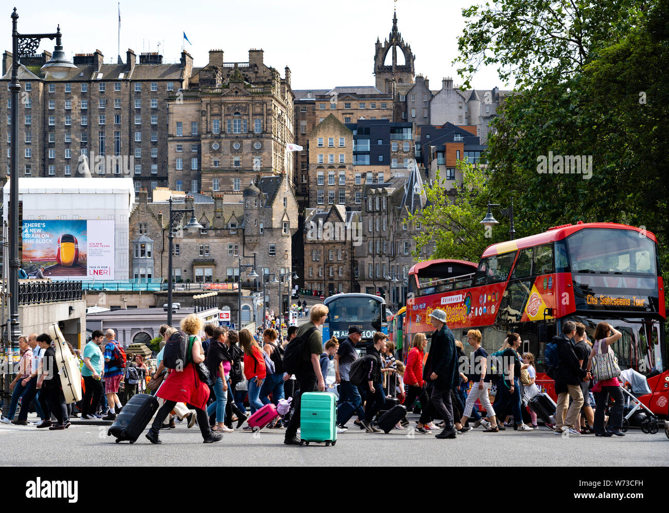 Pedoni che attraversano street a Princes Street con la Città Vecchia Edimburgo a posteriori, Scotland, Regno Unito Foto Stock