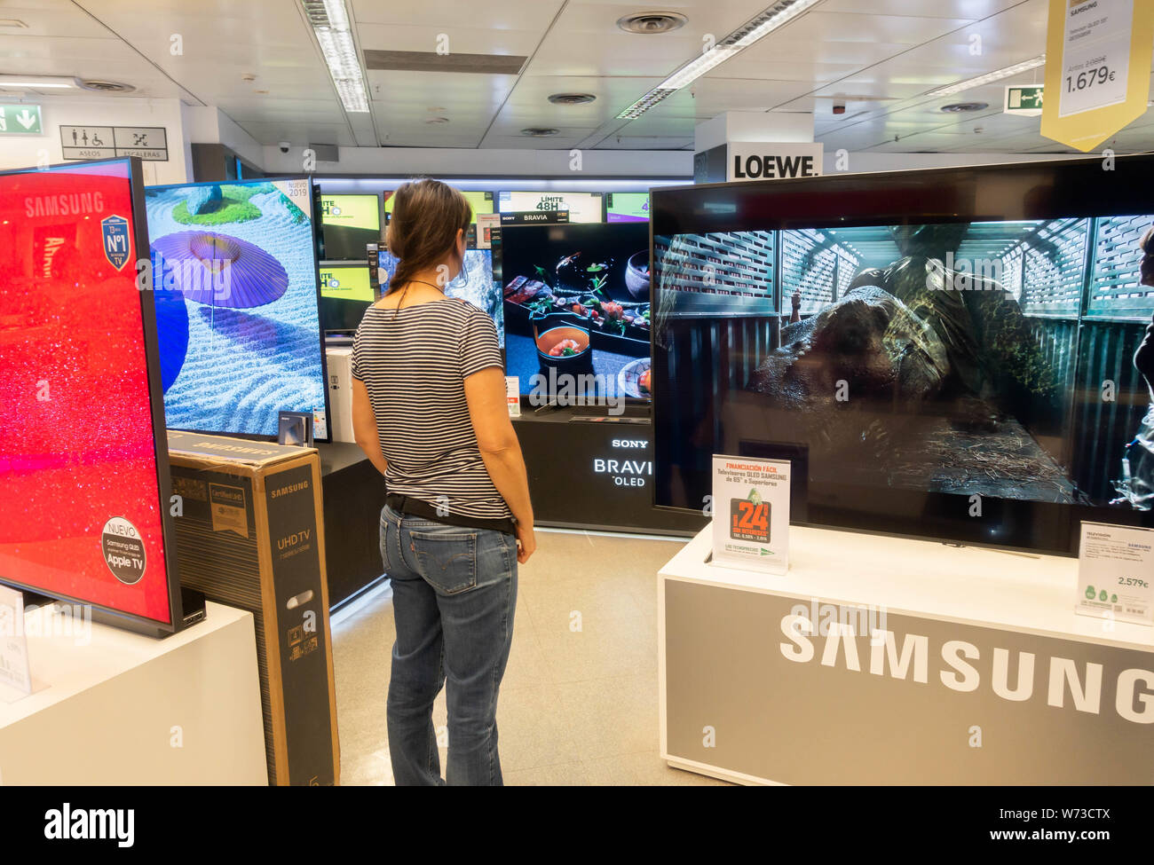 Donna che guarda al nuovo Samsung High definition 4k curva schermi TV in negozio elettrico Foto Stock