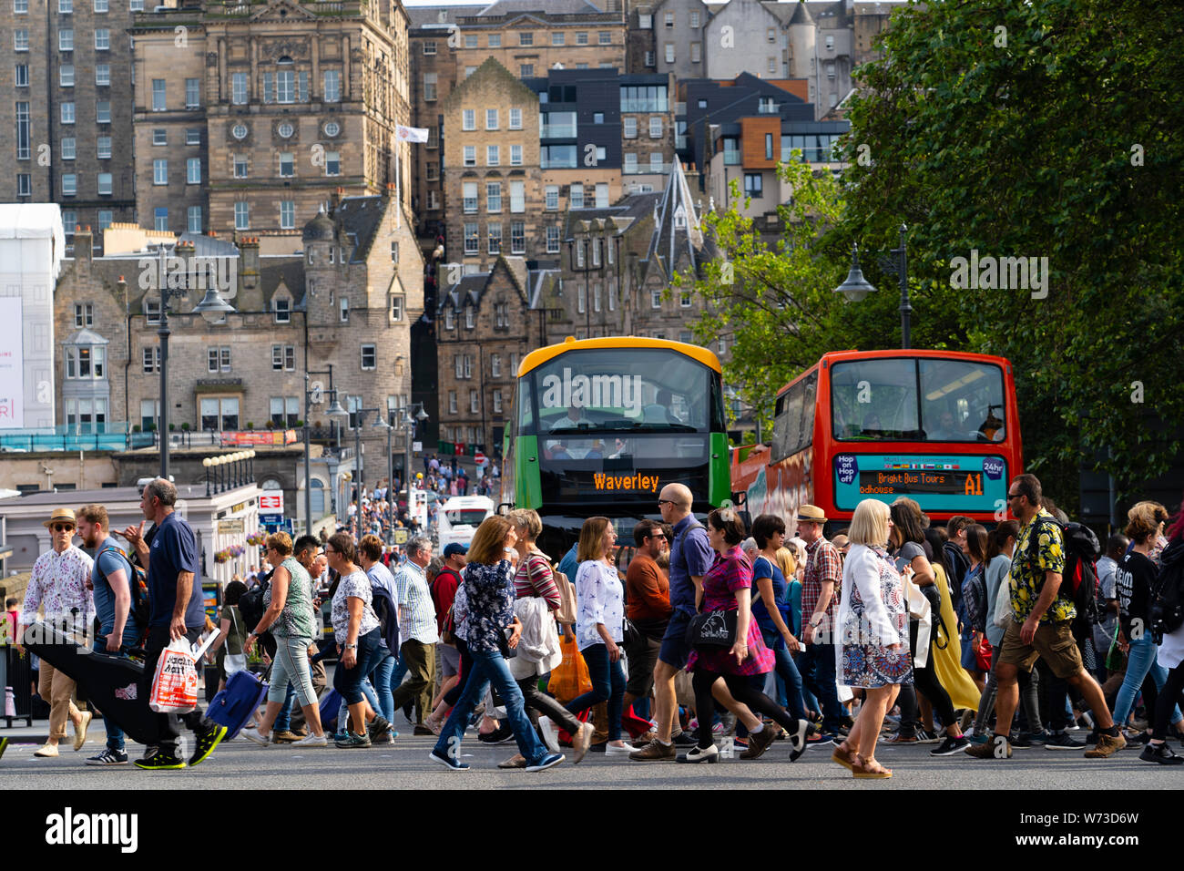 Pedoni che attraversano street a Princes Street con la Città Vecchia Edimburgo a posteriori, Scotland, Regno Unito Foto Stock