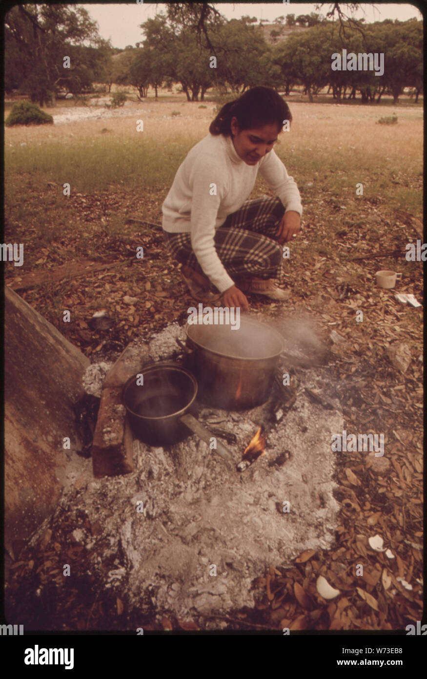 Moglie di una pecora itineranti SHEARER cuochi il suo pasto di mezzogiorno al di fuori della tenda in cui la sua famiglia vive. La SHEARER sta lavorando su un ranch in LEAKEY, Texas, e SAN ANTONIO AREA Foto Stock