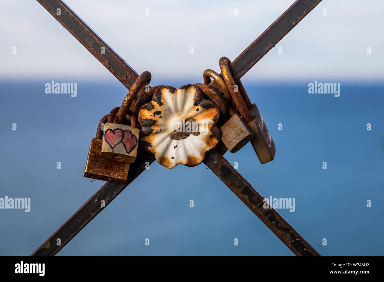 In alto sopra il mare blu livello sulla ringhiera arrugginito sono vecchio amore serrature, Peschici, Gargano in Puglia, Italia Foto Stock