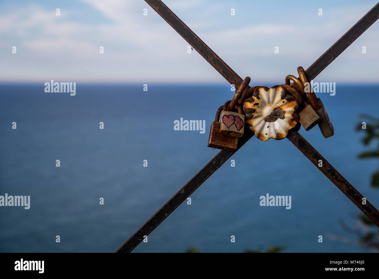In alto sopra il mare blu livello sulla ringhiera arrugginito sono vecchio amore serrature, Peschici, Gargano in Puglia, Italia Foto Stock
