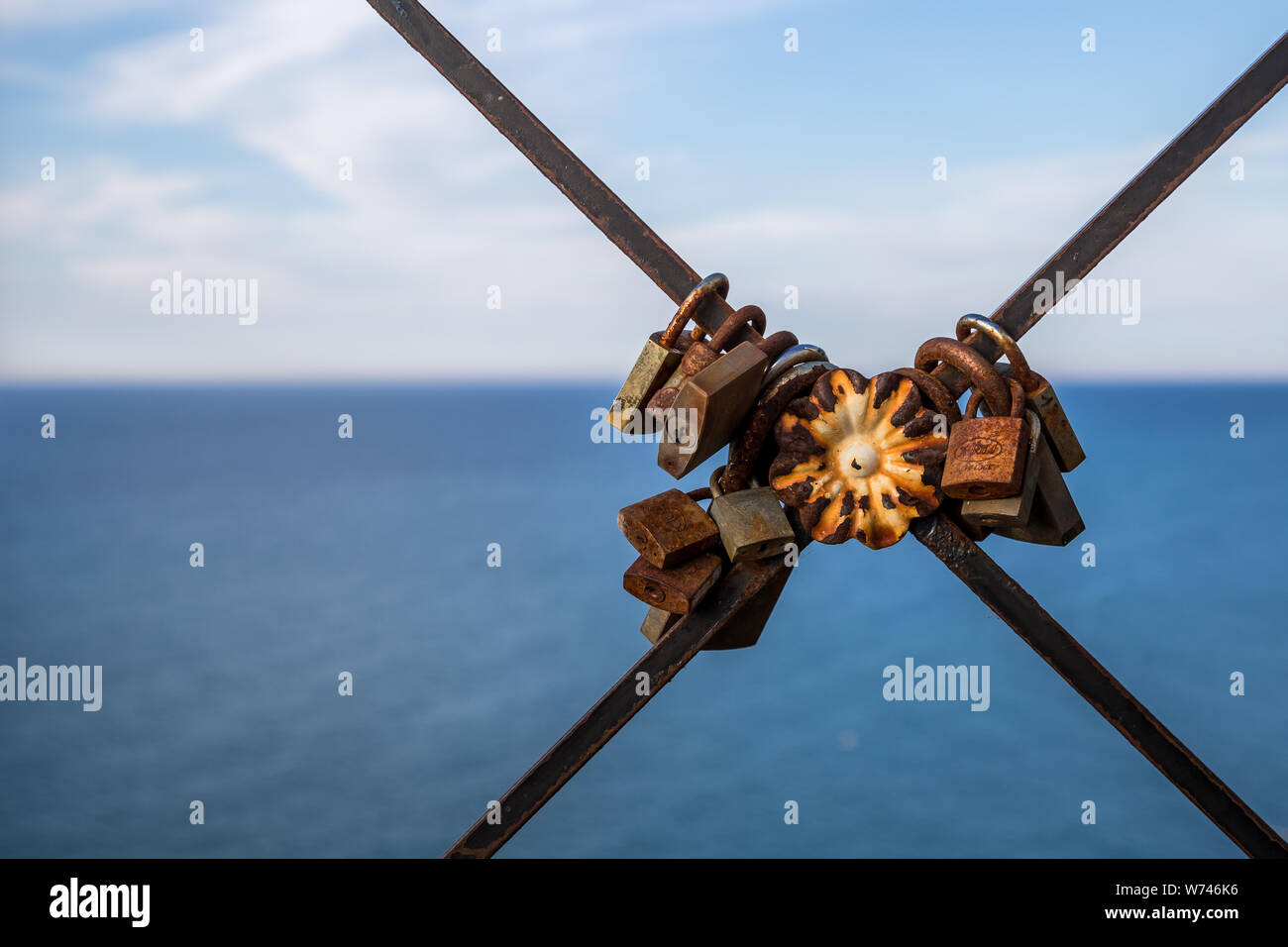 In alto sopra il mare blu livello sulla ringhiera arrugginito sono vecchio amore serrature, Peschici, Gargano in Puglia, Italia Foto Stock