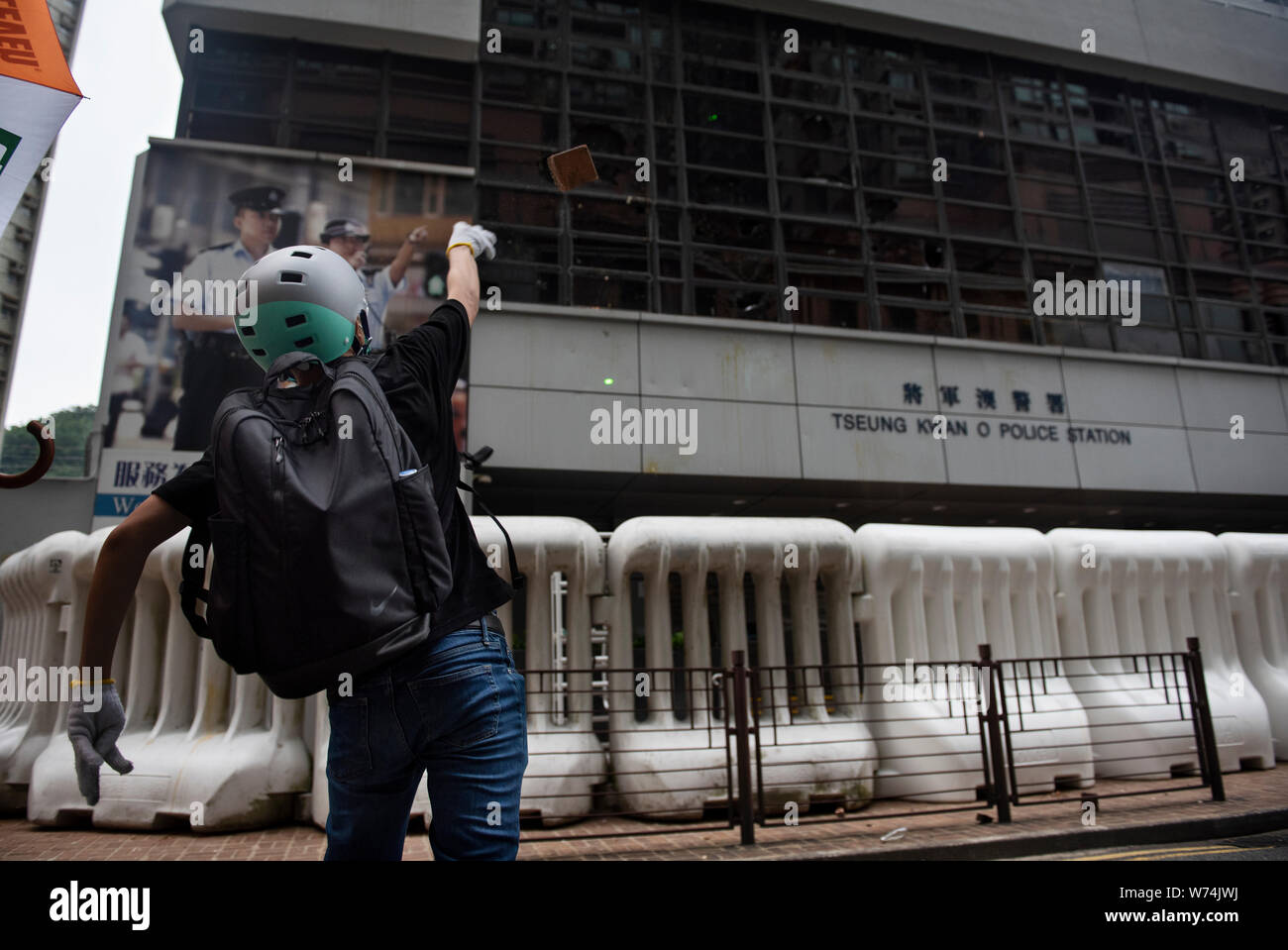 Un manifestante getta un mattone alla Tseung Kwan O stazione di polizia durante le manifestazioni.Hong Kong manifestanti hanno ignorato gli avvertimenti della polizia e ha continuato con la più recente serie di dimostrazioni mirate governo di Hong Kong e di numerose stazioni di polizia. Foto Stock
